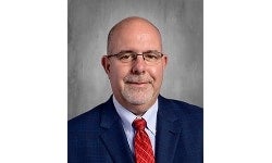 Portrait of Dr. James Woodard wearing a blue suit and red tie.