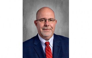 Portrait of Dr. James Woodard wearing a blue suit and red tie.