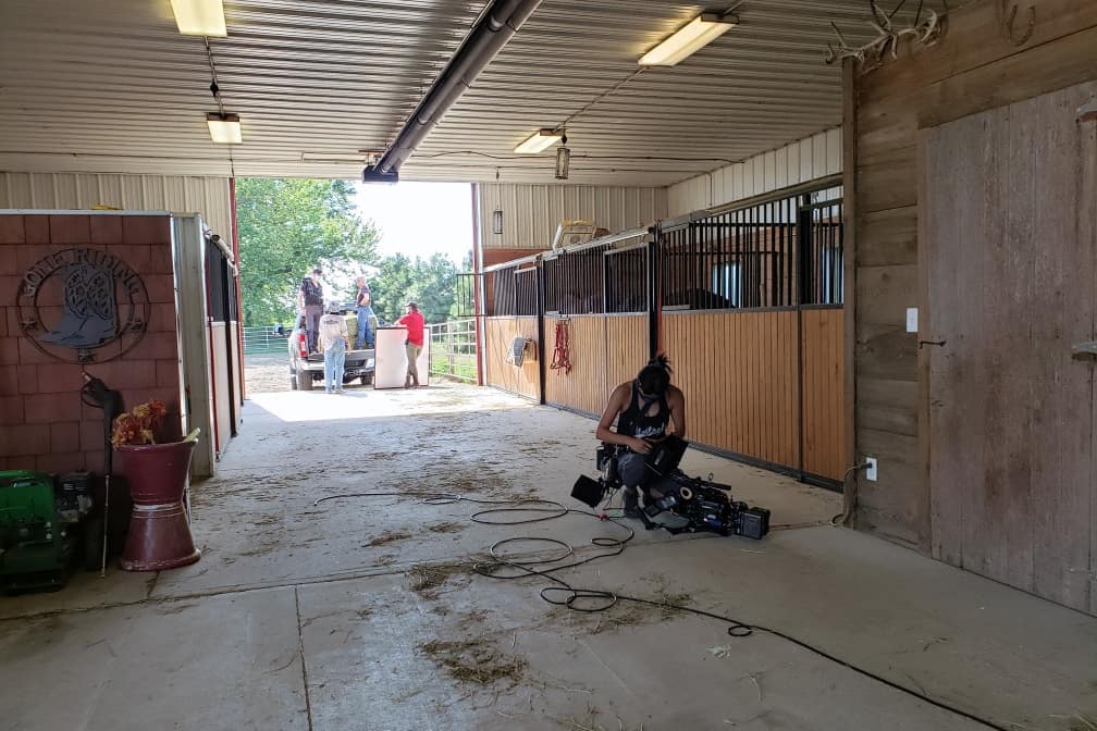 View inside of a horse barn as a camera operator prepares to film