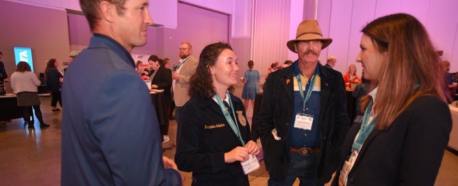 Four FFA Alumni talking at an event.