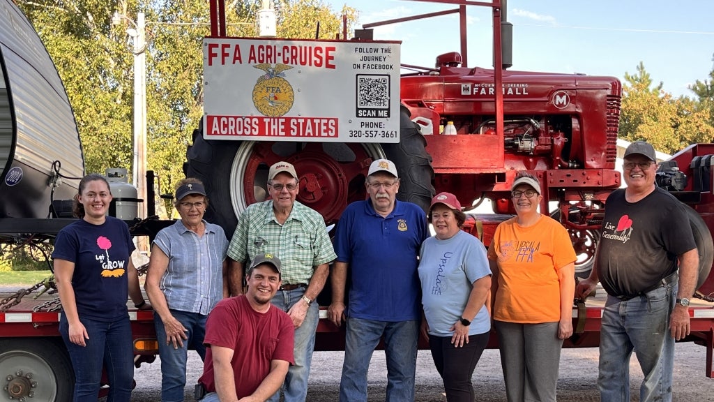 Upsala FFA Alumni members smile for a photo with Mark Koehn’s (far right) tractor. Photo courtesy of Mark Koehn.