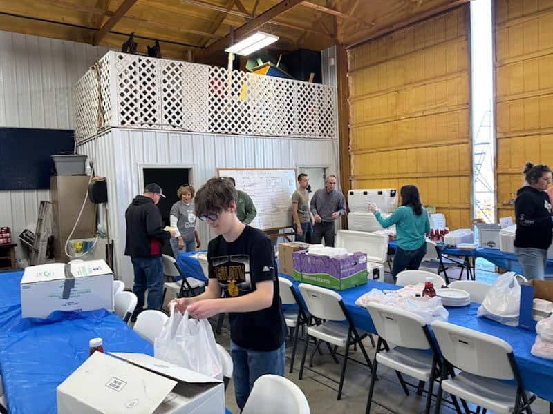 Graham (front center, wearing Galatia FFA merch) fills to‑go dessert orders at his chapter’s annual fish fry, meticulously counting pieces of cake, boxing them by size and labeling each for delivery.