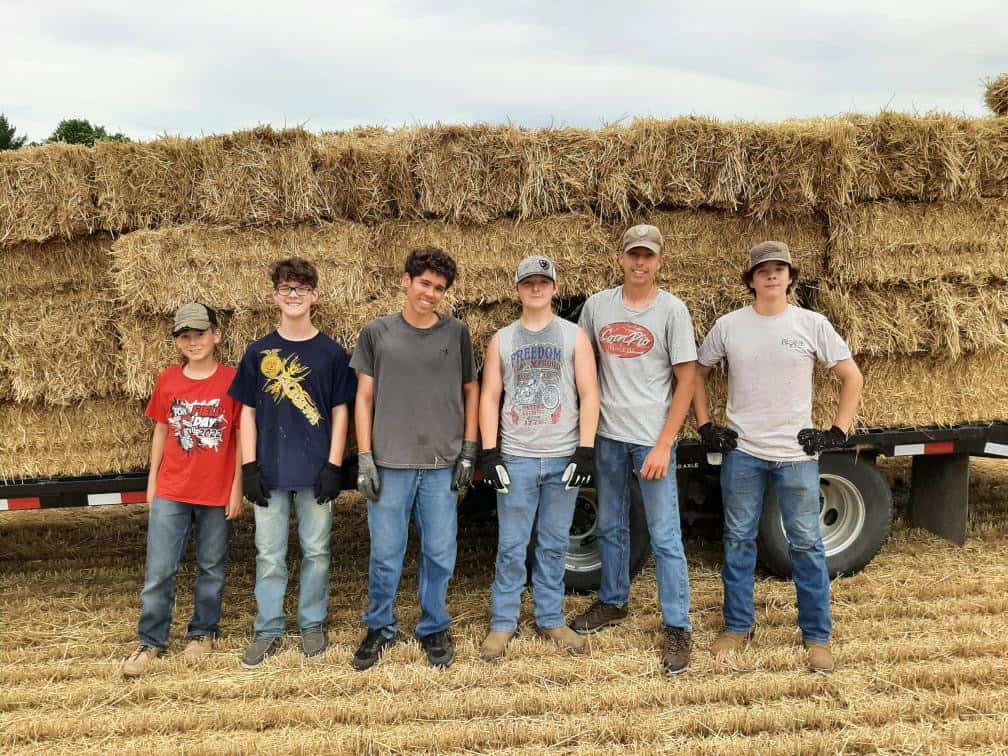Graham (second from left) and chapter members pick up straw bales for a fundraising drive, ultimately turning hard work into essential chapter funds and community service.