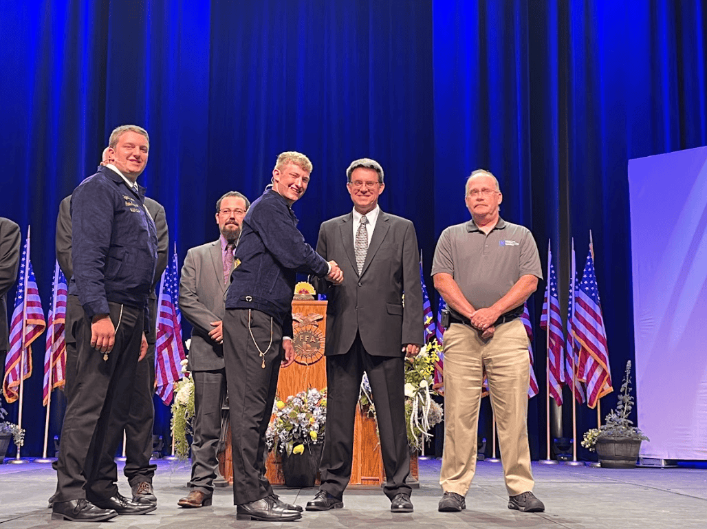 Mr. Steber receives recognition on stage for becoming the 2024 Illinois Golden Owl Award at the 2024 state convention. The 2023-24 Illinois State Treasurer Benjamin Bremmer and 2023-24 Illinois State President Thaddeus Bergschneider present this award to Steber.