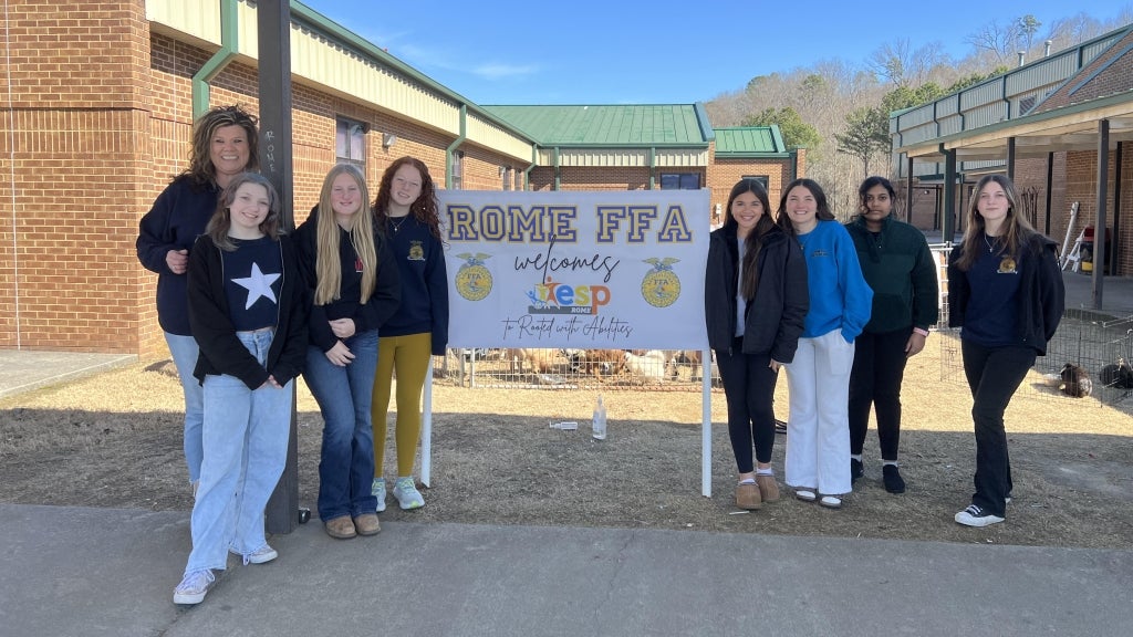 Rome Middle FFA members, including Avi-Kate Edwards (fourth from left), and advisor Ashley Hamby (far left) pose in front of a banner welcoming attendees to their chapter’s event. Photo courtesy of Rome Middle FFA.