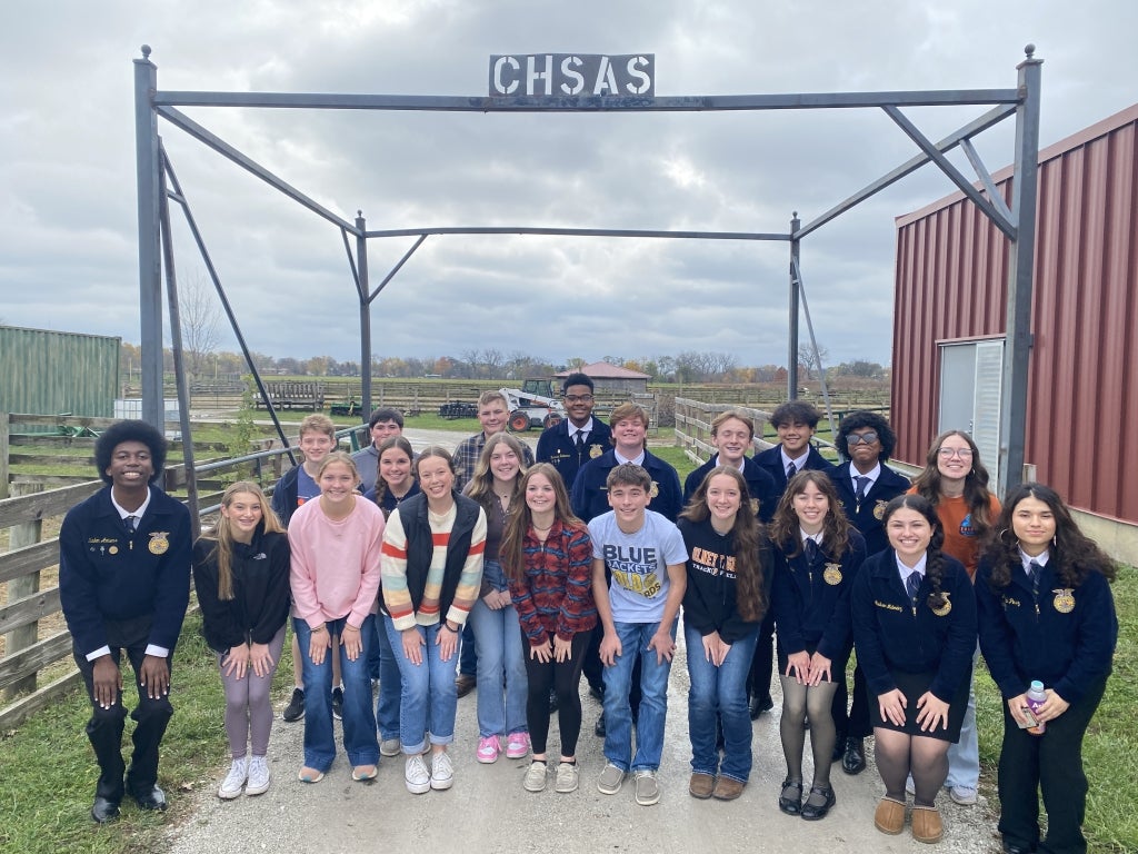 Olney FFA and Chicago High School for Agricultural Sciences FFA members pose for a picture in front of the farm gate.