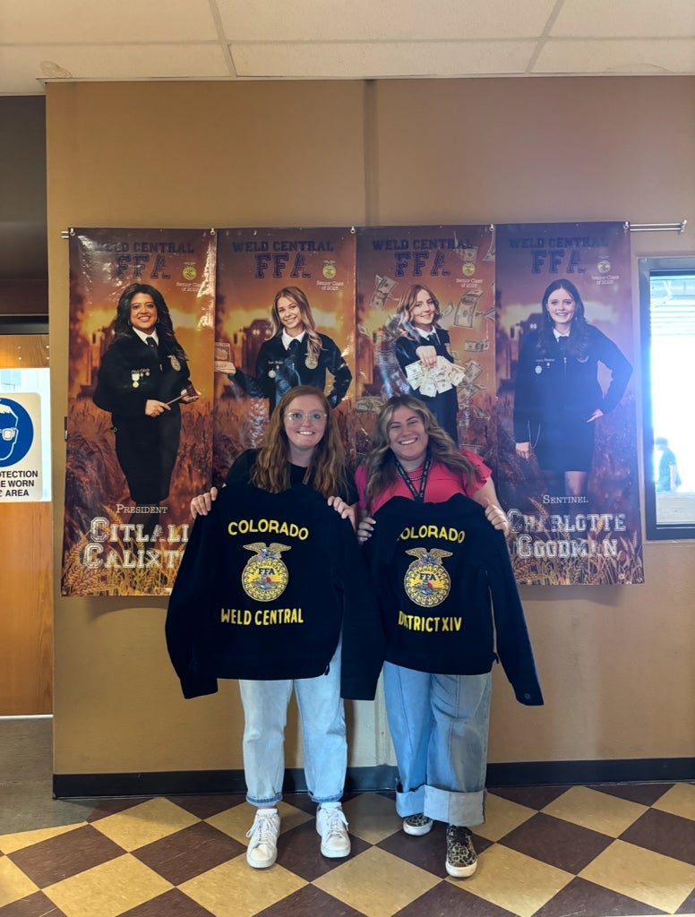 Madsen and Delmore smile while holding the Weld Central FFA chapter and corresponding district jackets.