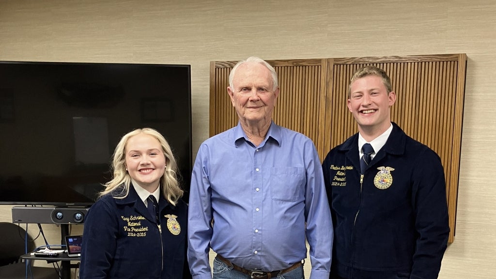 Harry Stine (center) smiles with 2024-25 National FFA Eastern Region Vice President Mary Schrieber (left) and 2024-25 National FFA President Thaddeus Bergschneider (right) during their visit to Stine Seed.