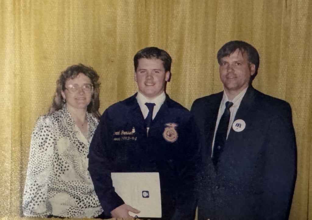 Brad Grossen (center) smiles with his American FFA Degree certificate. Photo courtesy of Kari Grossen.