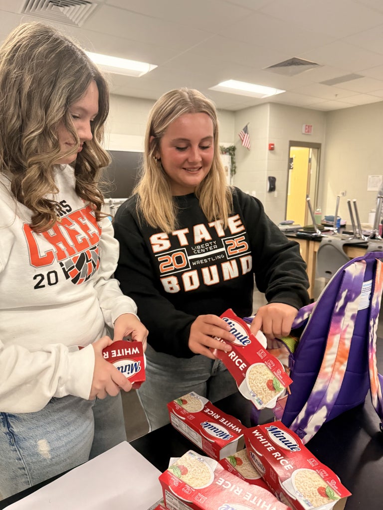 Liberty Center FFA Vice President Maddie Sattler and Historian Alyvia Meyer pack rice into the backpacks.