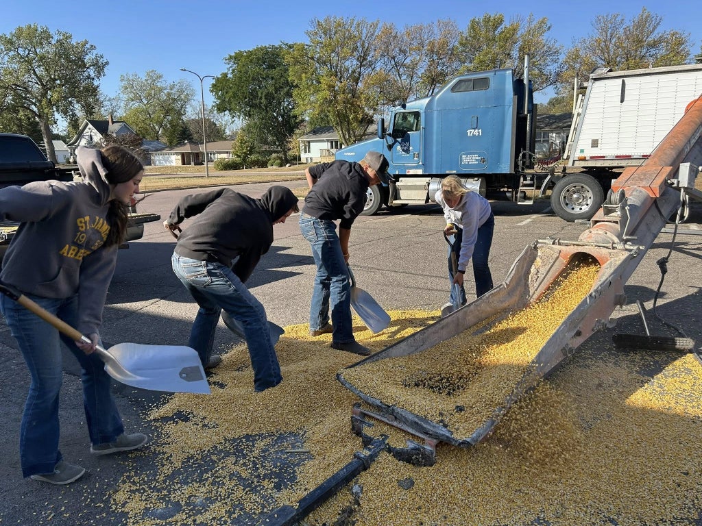Members work together to load donated corn into an auger, which deposits it into a grain trailer that will bring it to the local elevator at the end of the day.