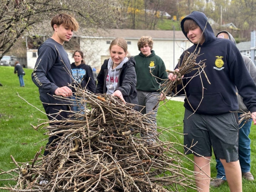 Chapter members work together to gather sticks in the grassy areas surrounding the facility.