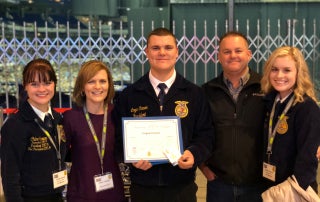 A picture of the Carver family standing with Logan after he received his American FFA Degree