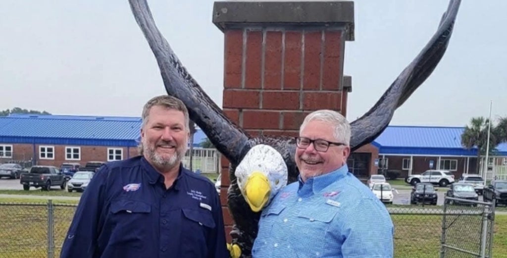 Cameron Asbell (right) stands next to John Meeks (left) in Front of an eagle statue they donated to Bronson Middle High School reflecting how they serve their community.