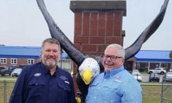 Cameron Asbell (right) stands next to John Meeks (left) in Front of an eagle statue they donated to Bronson Middle High School reflecting how they serve their community.