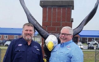 Cameron Asbell (right) stands next to John Meeks (left) in Front of an eagle statue they donated to Bronson Middle High School reflecting how they serve their community.
