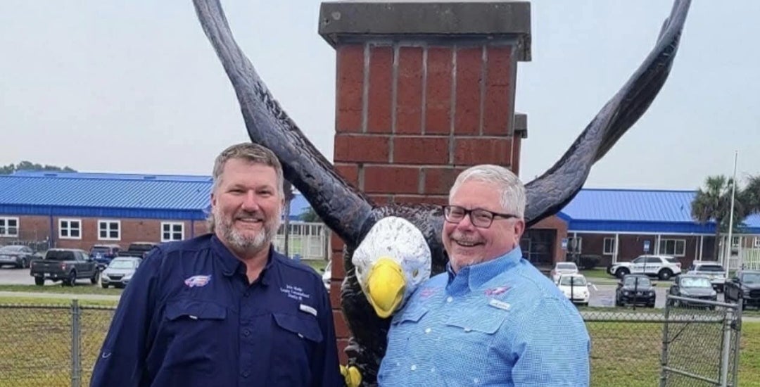 Cameron Asbell (right) stands next to John Meeks (left) in Front of an eagle statue they donated to Bronson Middle High School reflecting how they serve their community.