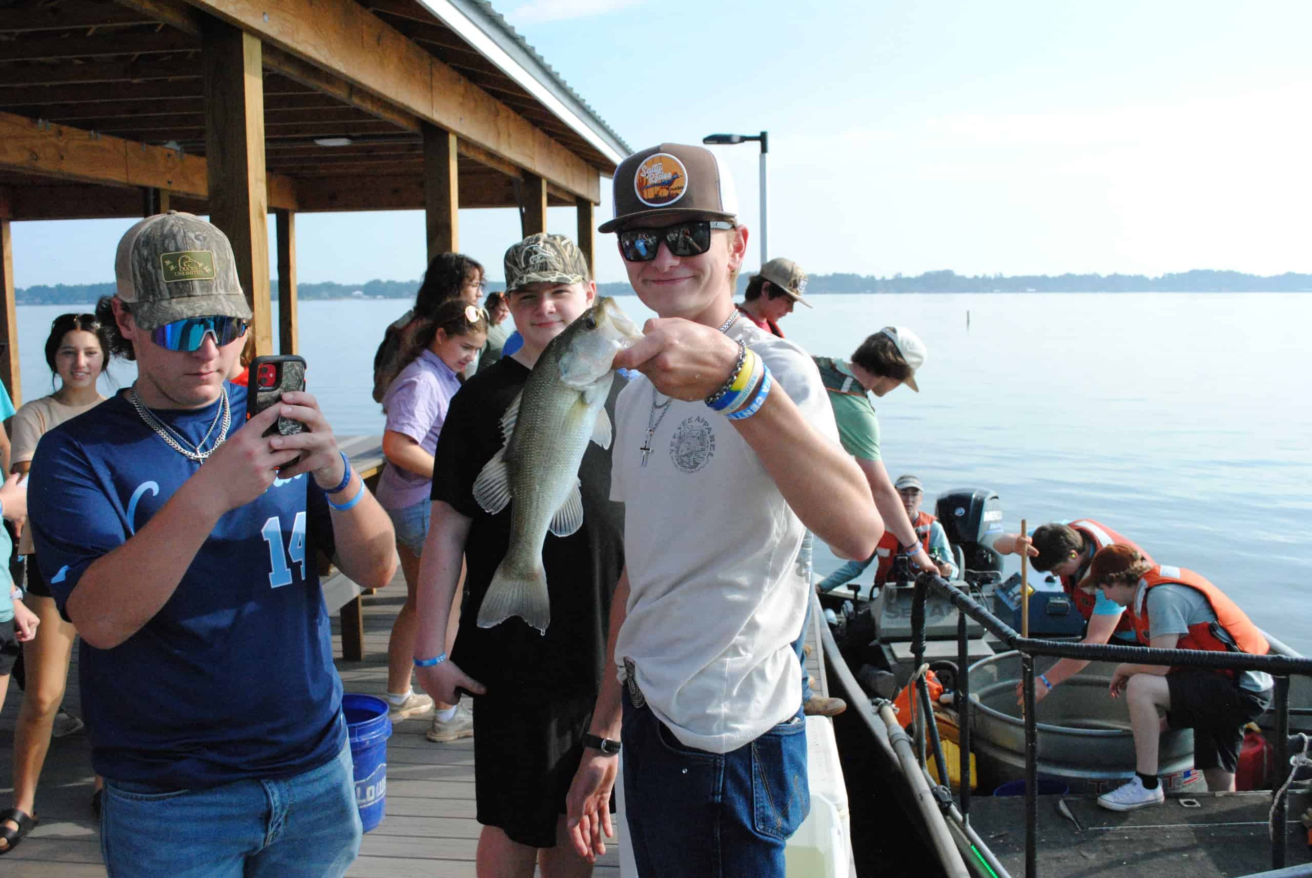 A student shows off the bass he caught during the fish survey, shock boat, small group rotation.