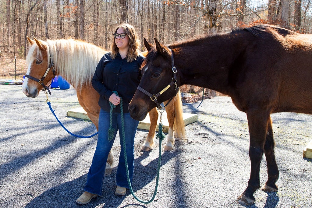 Dakota Theobald stands with Kenny and Buttons, two of the horses at Harmony Family Center.