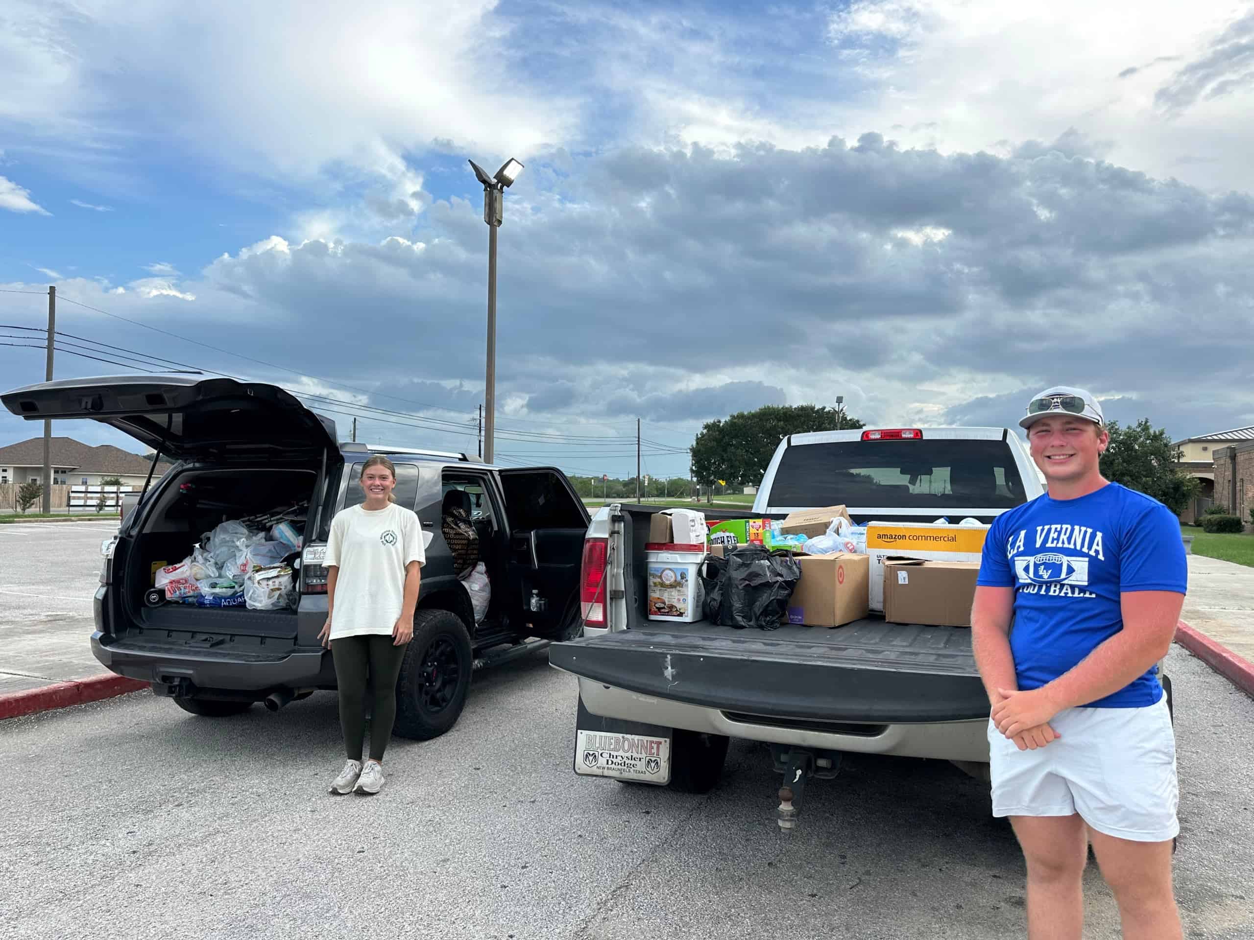 Peyton Dylla (right) standing in front of the two truckloads of supplies collected.