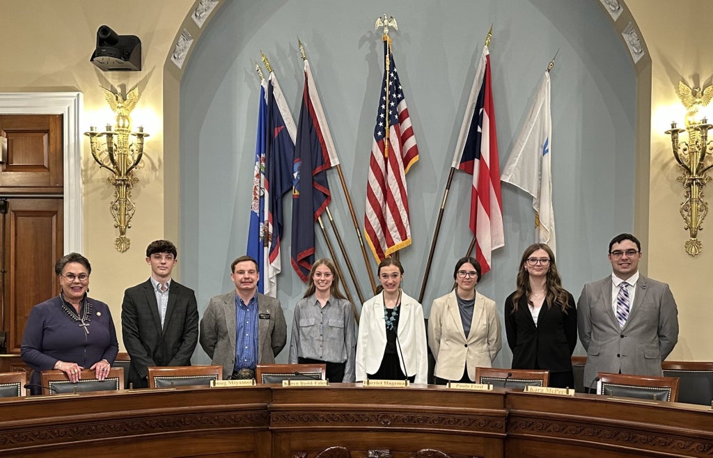 Members pose with Congresswoman Harriet Hageman in the meeting room of the House Committee on Natural Resources.