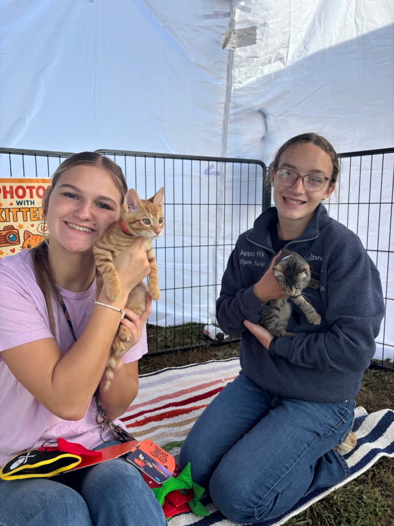 Members Isabella Linsmeier and Alyson Hackett showcasing two rescued kittens for adoption.