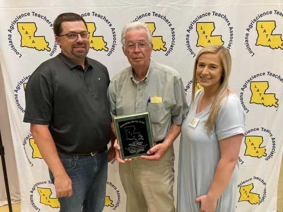 Wesley Sebren (left), Donny Sebren (middle) and Ashlee Sebren (right) smile after Donny received the Louisiana Agriscience Teacher Association Educator Retirement plaque.