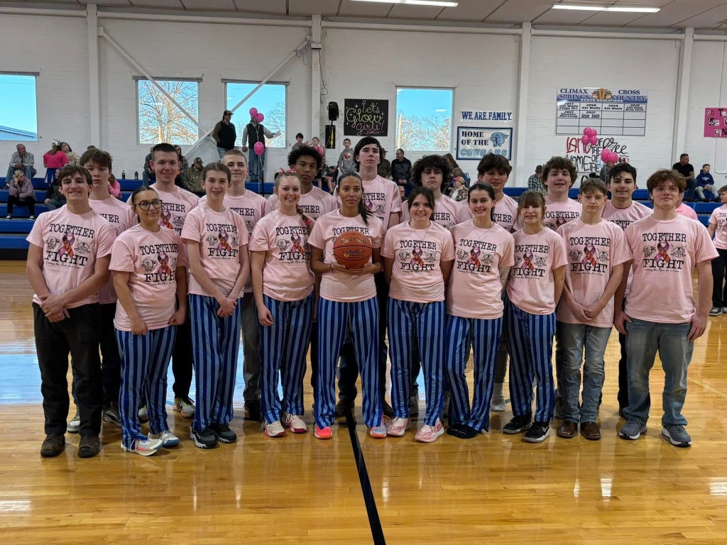 The Climax Springs basketball teams wear their Pink Out shirts before their game. The founder, DeNay Blanche, is in the middle and holding the basketball.