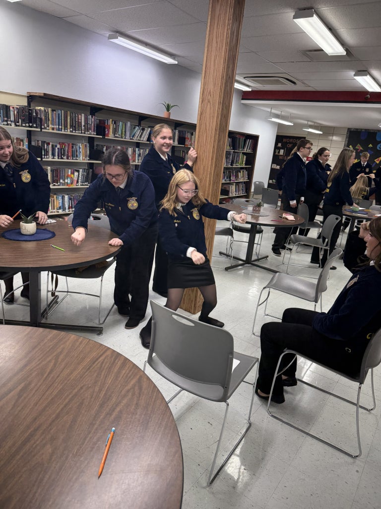 A group of members act out the career shown about their peers head!