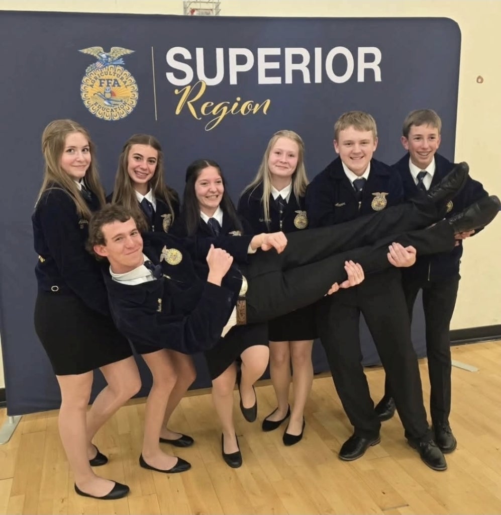 Susanville FFA's Novice Parliamentary Procedure team celebrating winning first place at regionals, holding their coach Tucker Bailey