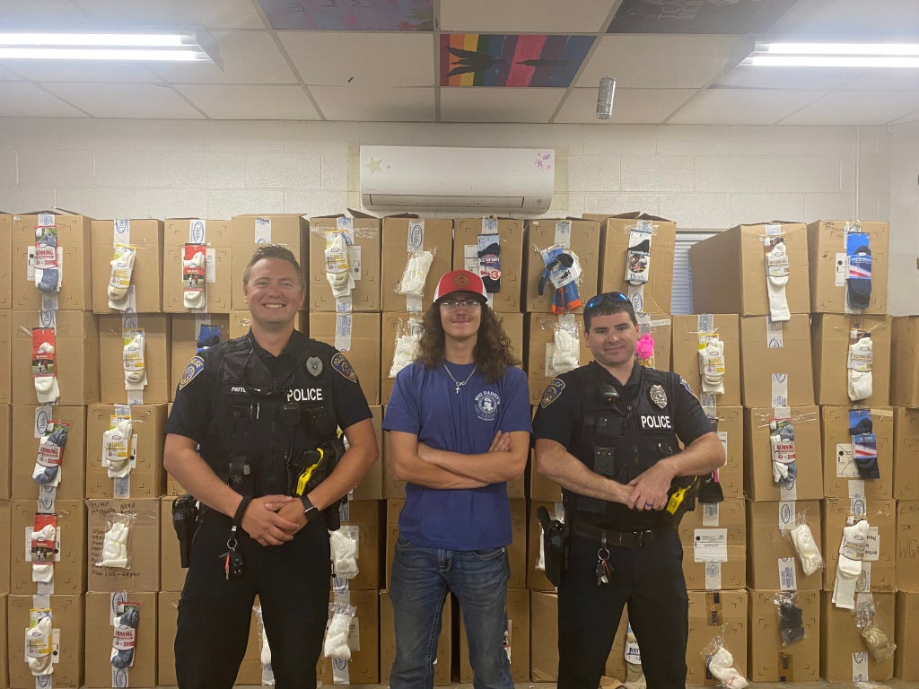 South Iredell FFA Reporter Carson Ball (center) stands with local law enforcement in front of thousands of pairs of socks organized for donation.