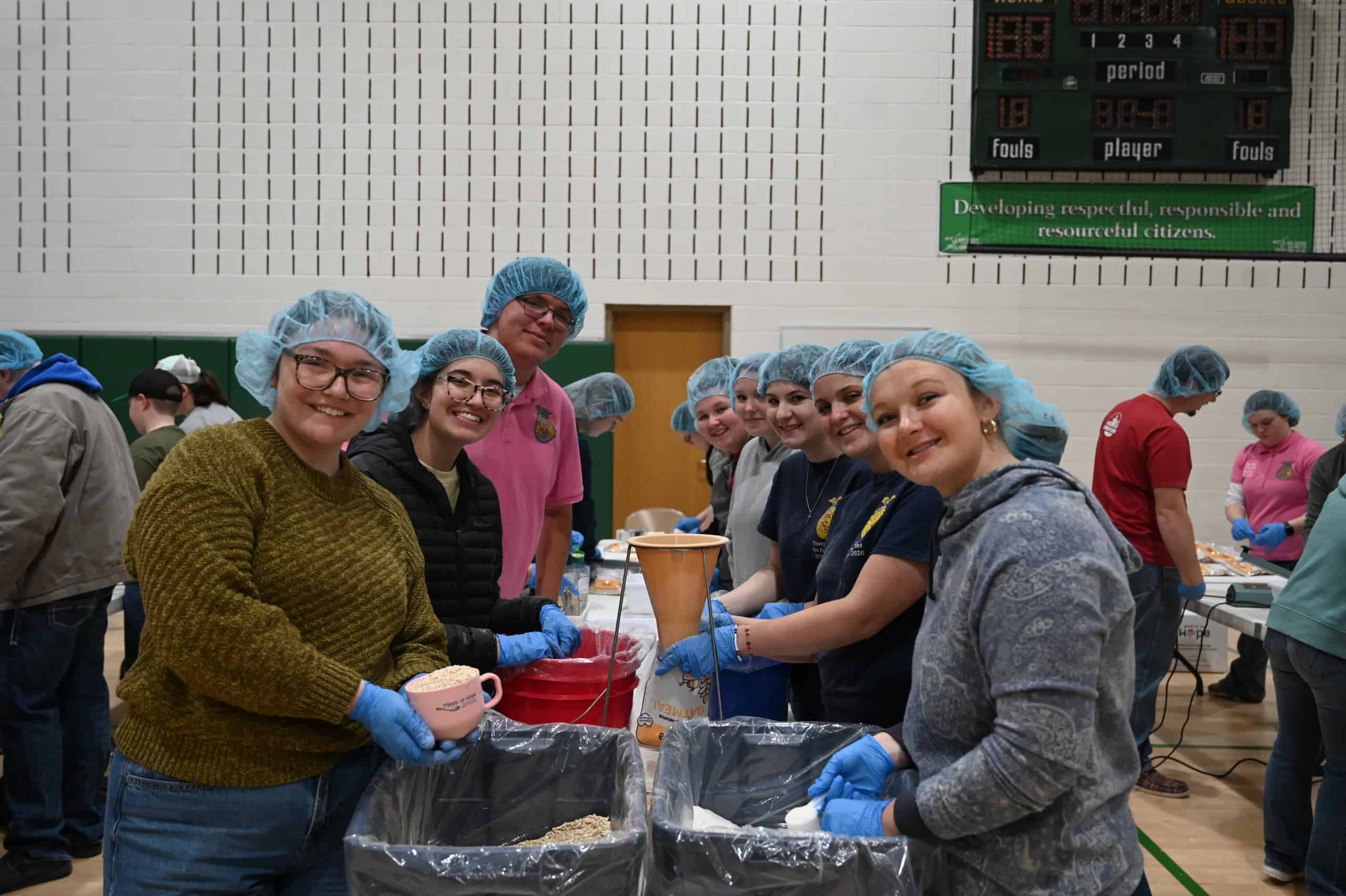 Ethan Sheets (wearing the pink polo) stands with volunteers during the meal packing event.