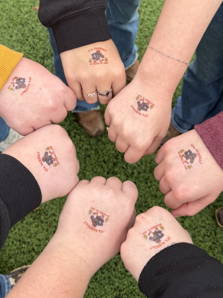 Seven Virginia FFA members displaying their "Virginia Tech FFA Game Day" temporary tattoos on their hands.