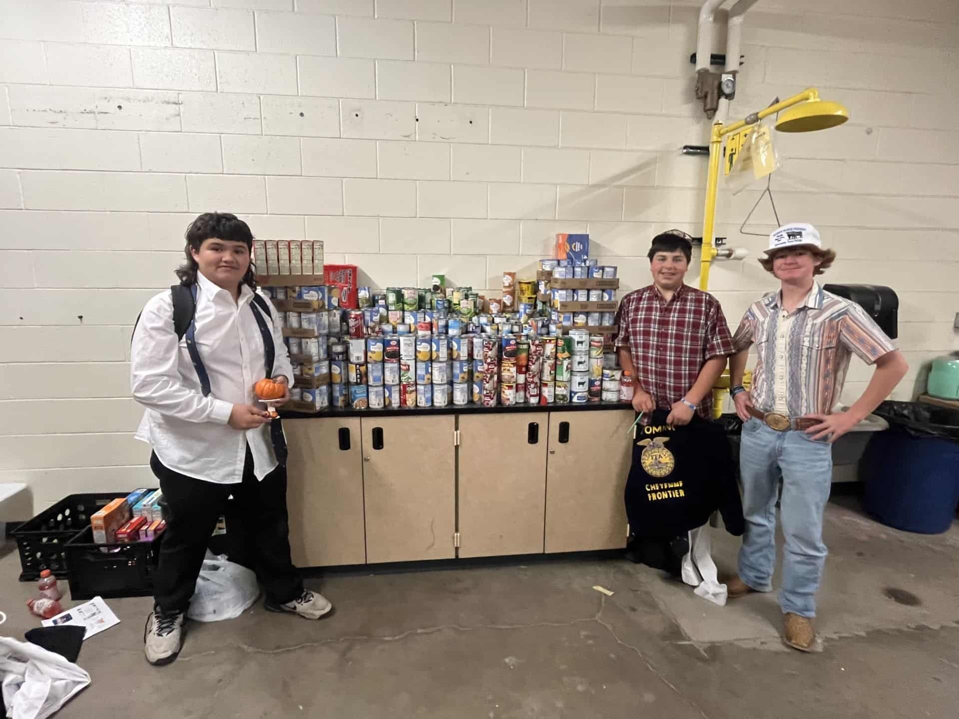 Dion Tail (left), Cruz Medina (center) and Colton Wolski (right) pose in front of a pile of cans to be donated. 