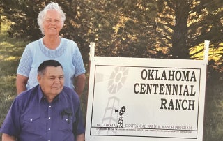 Joe White and his wife Joy White next to a sign for their Centennial Ranch.