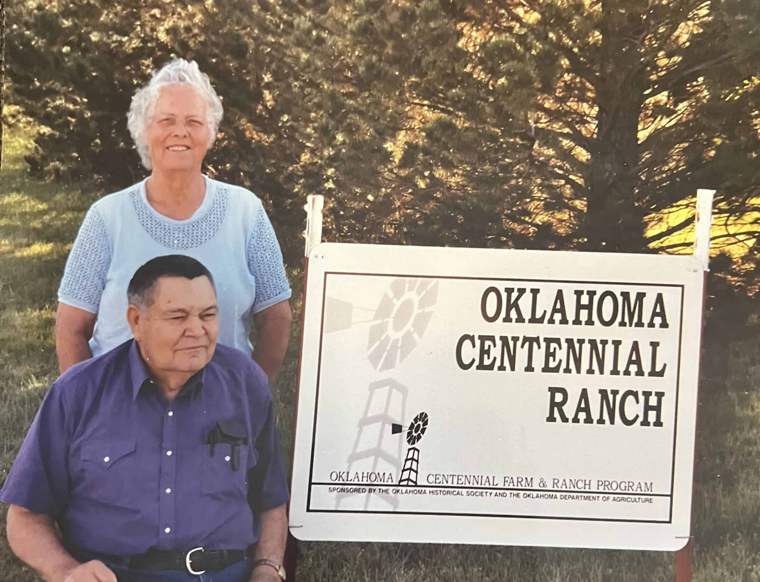 Joe White and his wife Joy White next to a sign for their Centennial Ranch.