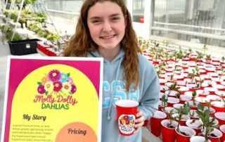 Molly posing next to her sign and plants