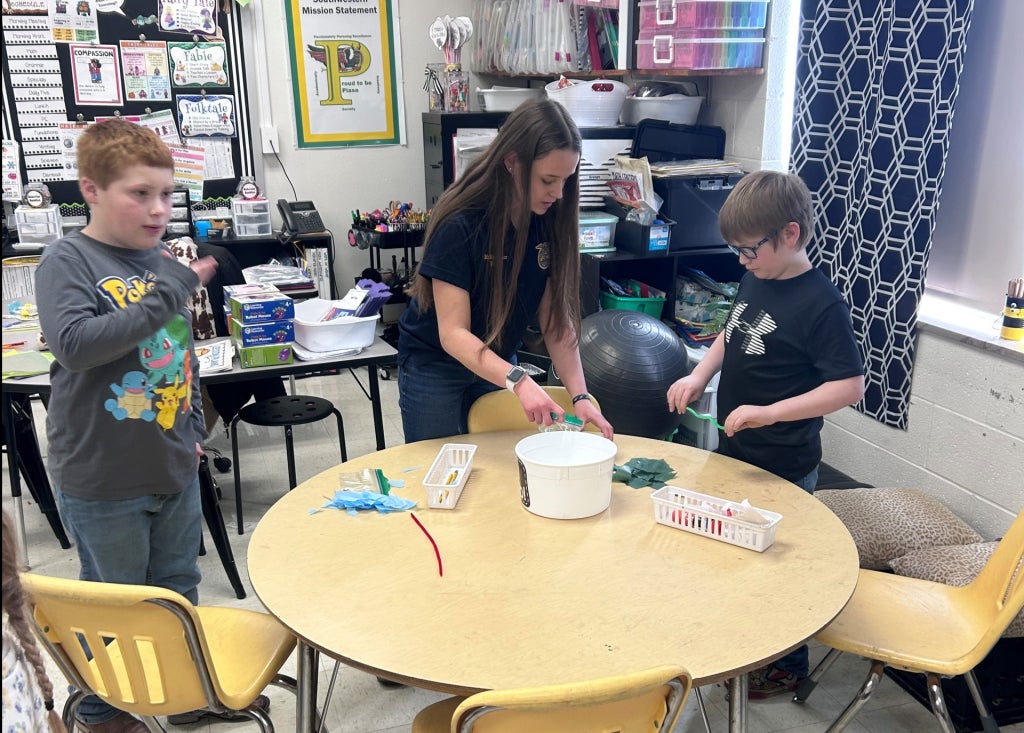A Southwestern FFA officer helps a student create a "butterfly in a bag" during the classroom activity.