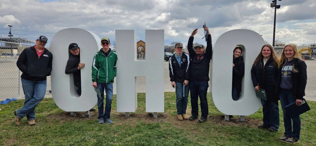 Ohio FFA District 8 members pose together outdoors beside large “Ohio” letters.