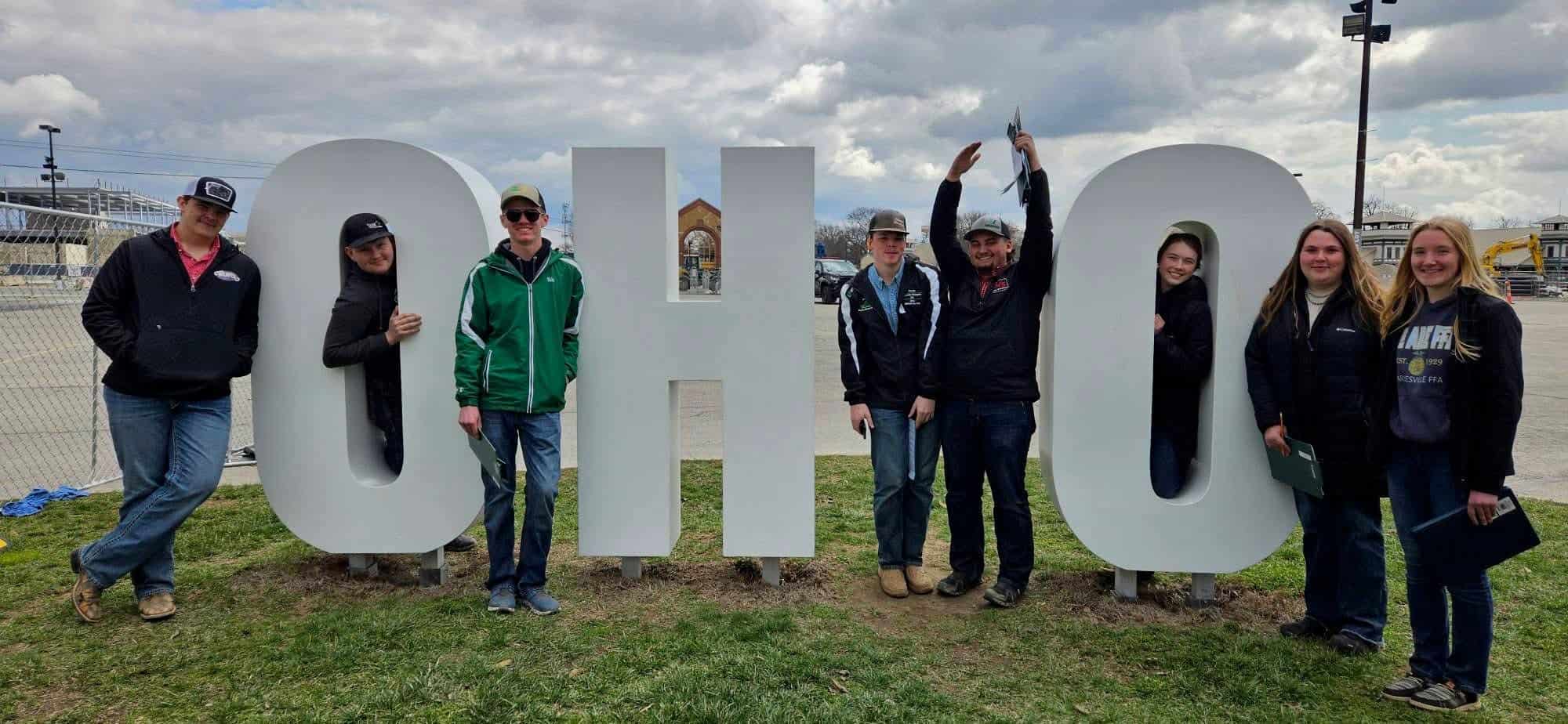 Ohio FFA District 8 members pose together outdoors beside large “Ohio” letters.
