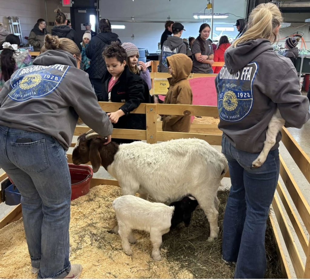 Shae Lefers (left) and Katherine Marshall (right) holding goats for students to pet.