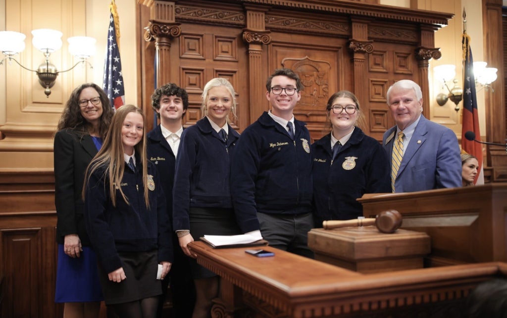 Members stand on the floor of the Georgia House of Representatives with Speaker of the House Jon Burns.