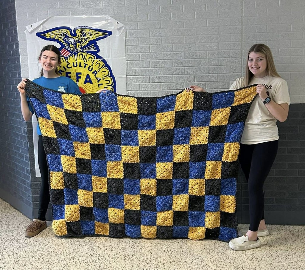 Kacie Swearingin (left) proudly holds the blanket she donated to this year’s cancer auction. A dedicated leader since the beginning of her FFA journey, Swearingin, now only a high school sophomore, has already made a meaningful impact on countless lives.