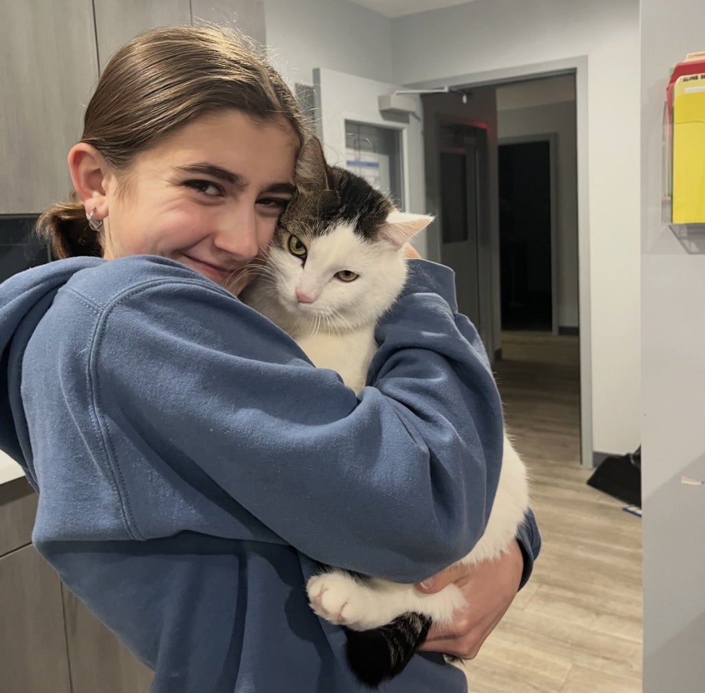 Christenson is seen with a cat while she works at a local animal shelter, which inspired her to create AniMend.