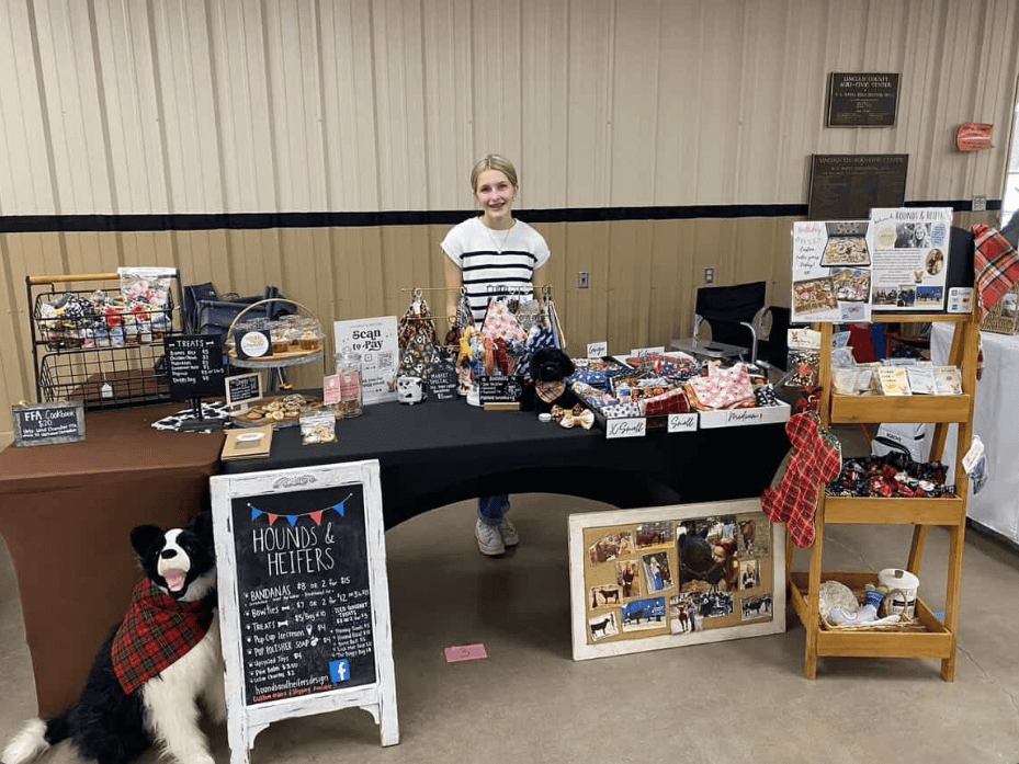 Ava sets up her products at an indoor booth.