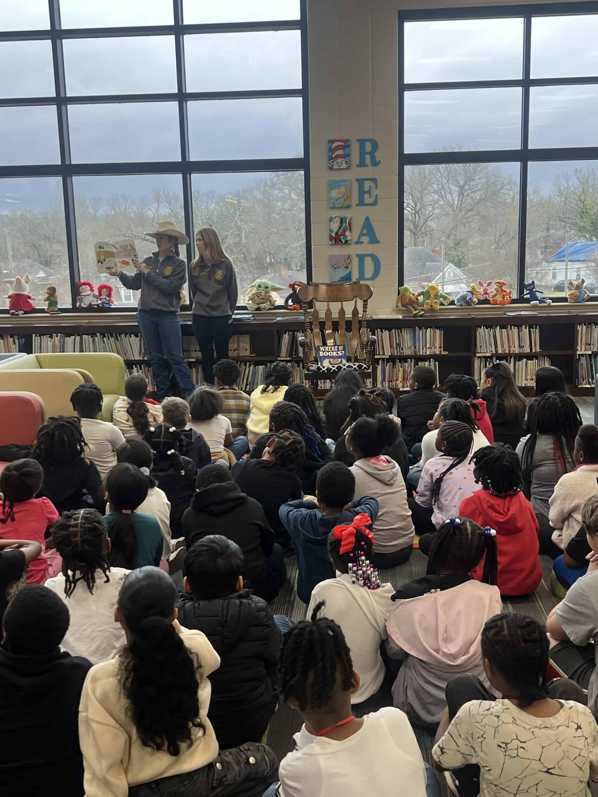 Two officers read a book to a group of elementary students.