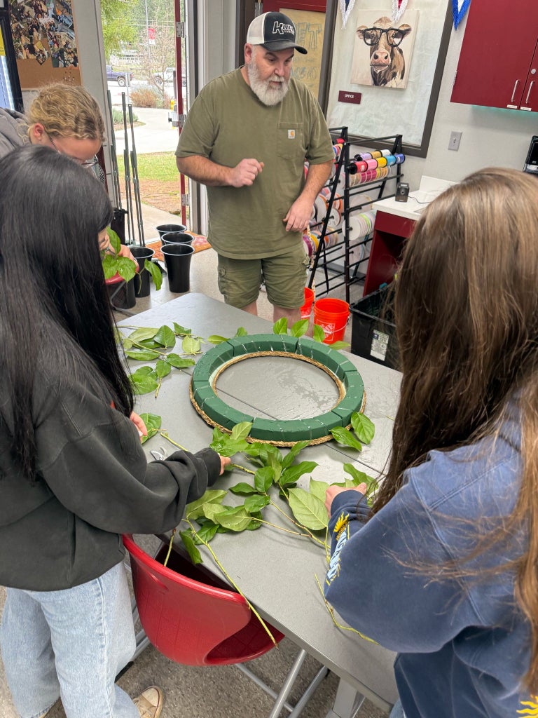 Mark Heer, owner of Forever Yours Flowers and Gift Shop, guiding students on the steps to make a wreath.