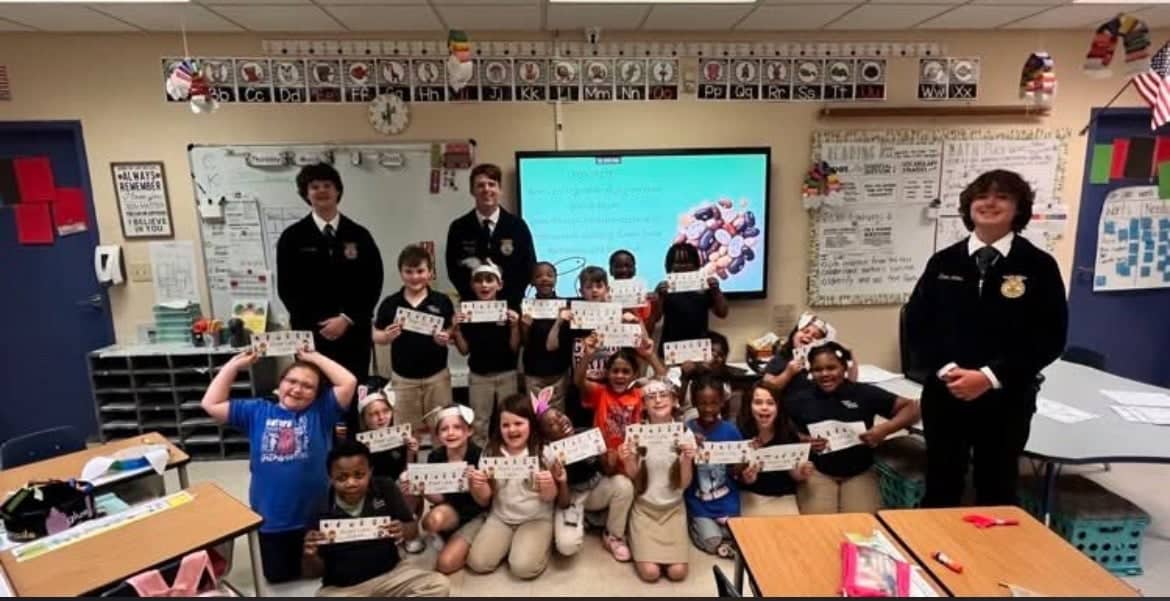 Delhi Charter FFA members Crestin Knight, Zachary Bailey and Kasen Simms educate second graders about the life cycle of a bean plant.