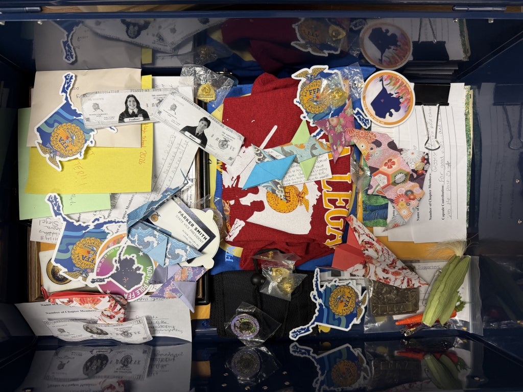 A top-down view of the time capsule’s contents before being closed. Stickers, notes, buckles, shirts and pins can be spotted throughout.