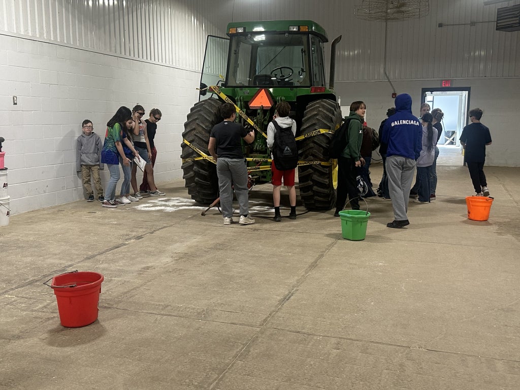 Flour outlines the "body," and crime scene tape is wrapped around the tractor while students solve the mystery.